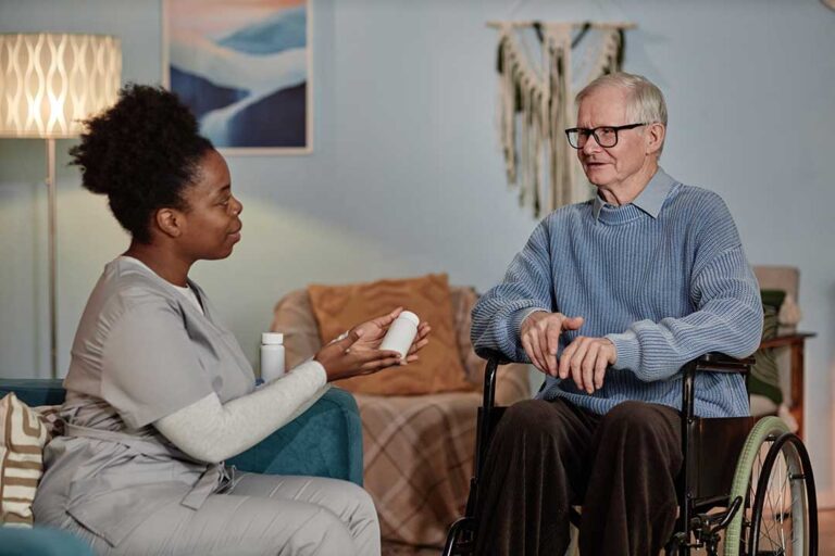 An older adult and family member sitting at a kitchen table reviewing paperwork together.